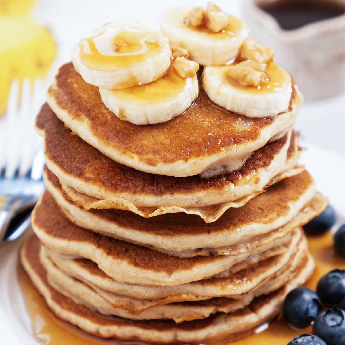 A stack of Emily's high-protein pancakes topped with banana and honey